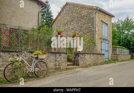 Feneyrols, Midi Pirenei, Francia - Luglio 23, 2017: vecchia bicicletta decorato con fiori in appoggio sulla facciata di un rustico di una casa di villaggio Foto Stock