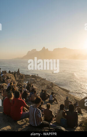 La folla si sono riuniti per guardare il tramonto da Arpoador Rock, Rio de Janeiro Foto Stock