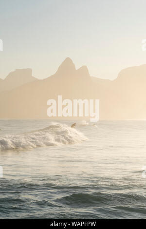 Un lone surfer presso la spiaggia di Ipanema, Rio de Janeiro durante un vago tramonto Foto Stock