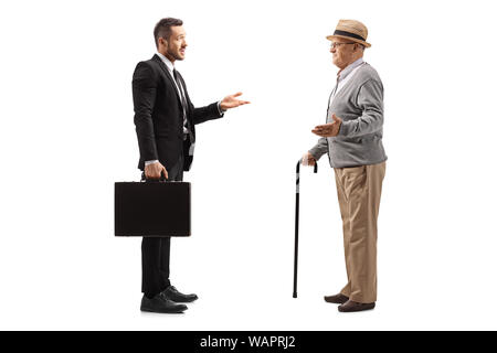 Lunghezza piena ripresa di profilo di un imprenditore con una valigia avente una conversazione con un anziano gentiluomo isolati su sfondo bianco Foto Stock