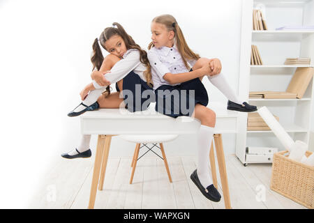 Una noiosa lezione. Carino scuola bambini seduti a tavola. Poco studentesse stanchi di lezione nella scuola primaria. Le piccole bambine essere annoiati durante la lezione scolastica. Più noiosa lezione mai. Foto Stock