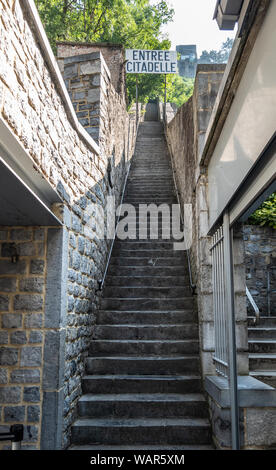 Dinant, Belgio - 26 Giugno 2019: Ingresso alla lunga naroow brown una scalinata di pietra fino alla cittadella, catturata nel verde fogliame. Primo piano. Foto Stock