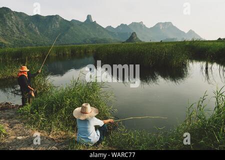 Pescatore di flusso nella parte anteriore della montagna, persone indossano hat e tenendo il bambù canna da pesca a Khao sam roi yot national park Foto Stock