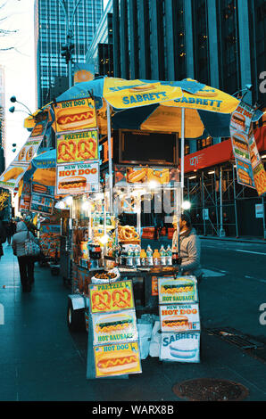 Venditore ambulante in New York City vendono hotdog e salatini dal suo street food cart. Foto Stock