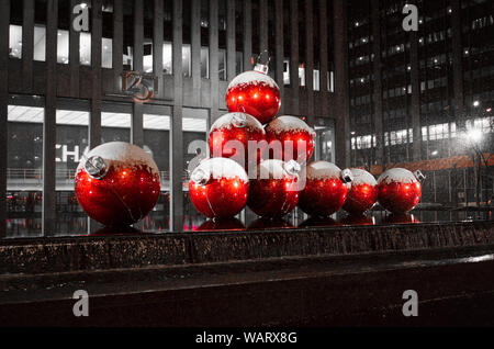 Grande Snow capped Ornamenti natale struttura è in mostra a New York City in un inverno nevoso di notte. Foto Stock