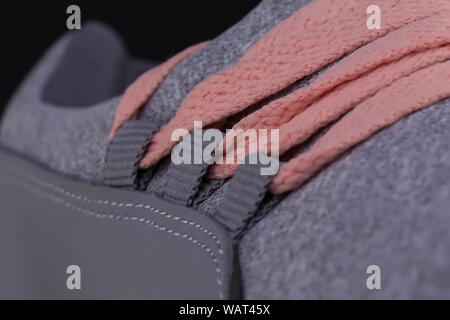 Un frammento di un grigio sneaker con lacci rosa vicino. Texture sneaker Foto Stock