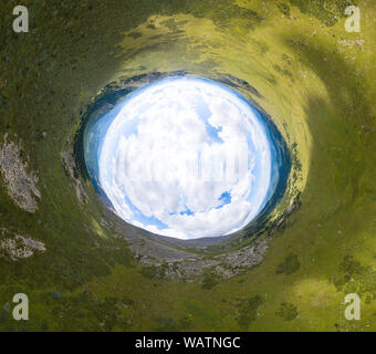 360 grado immagine panoramica di un mondo astratto rovesciato con il verde dei prati intorno a un ovale sky con le nuvole Foto Stock