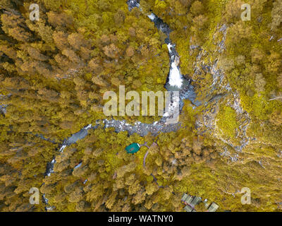 Una grande cascata nel retro delle montagne di Altai vicino a una ripida scogliera con alberi di giallo, house e il tetto verde. Il riposo e la solitudine mentre viaggia t Foto Stock