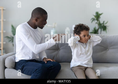 Arrabbiato singola nero padre scolding testardo pignolo piccolo figlio africana Foto Stock