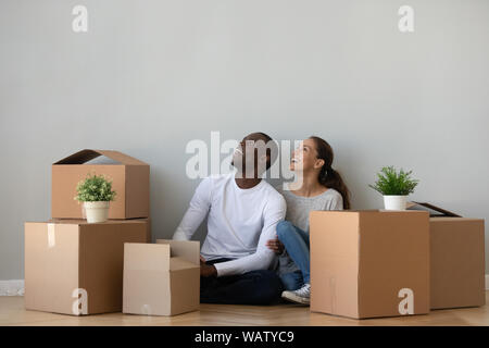 Eccitato etnia miste paio di sognare in casa propria con scatole Foto Stock