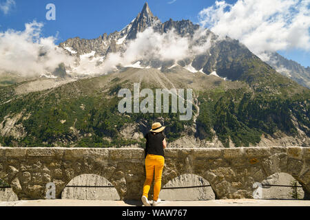 Un turista da dietro ammirando la vista di Aiguilles du Dru, una montagna del massiccio del Monte Bianco nelle Alpi francesi, Montenvers, Chamonix, Francia Foto Stock