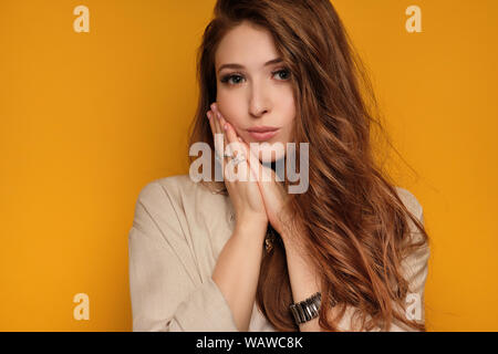 Ritratto di una ragazza redhead premendo il suo Palm per la sua guancia e guardando nella telecamera. Foto Stock