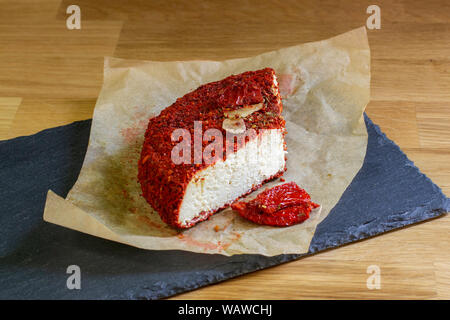 Gli agricoltori di ricotta con pomodori secchi e aglio. Fetta di fattoria di formaggio di capra ricotta su carta marrone Foto Stock