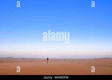 Un uomo è in piedi da solo in Al Wathba deserto. Abu Dhabi. Foto Stock