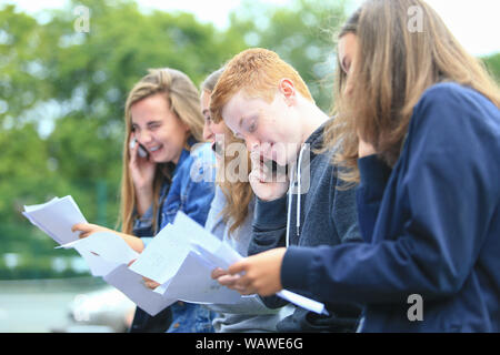 GCSE risultati esame giorno. Gli studenti con i risultati dei loro esami lettere al di fuori di una scuola secondaria Foto Stock