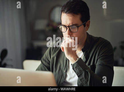 Ritratto di focus uomo al lavoro sul portatile a casa Foto Stock