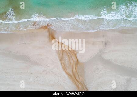 Creek con rossastro acqua ferruginosa scorre su di una spiaggia di sabbia nel mare, vicino a Stornoway, isola di Lewis e Harris, Scozia, Gran Bretagna, grande Foto Stock