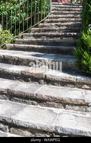 Un set di weathered giardino dei passi effettuati da Sydney arenaria che conduce verso l'alto con un telaio in acciaio verniciato ringhiera di protezione sul lato sinistro e il verde su entrambi i lati Foto Stock