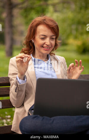 Una donna matura, tenendo le Sue mani fino in 'perfetto' gesticolando a qualcuno su laptop (conferenza video chiamata). Foto Stock
