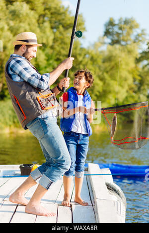 Figlio sensazione emozionato dopo la cattura del pesce con papà Foto Stock