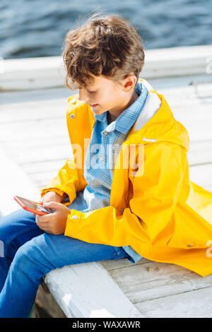 Dai capelli scuri boy giochi sul suo smartphone Foto Stock