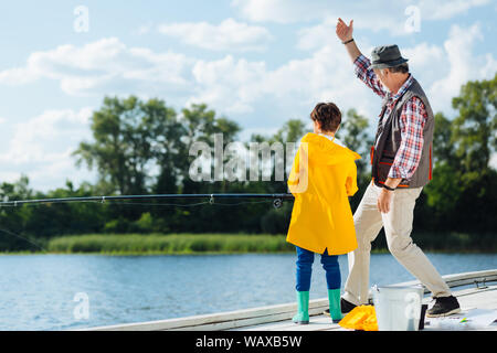 Ragazzo che indossa un impermeabile giallo tenendo la pesca Foto Stock