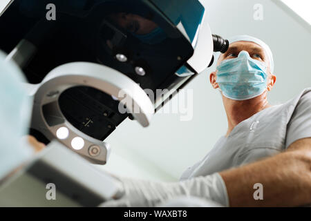 Basso angolo di un maschio adulto medico di indossare una maschera Foto Stock