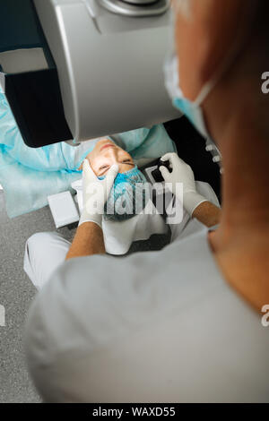 Maschio professionale medico il controllo dei suoi pazienti occhi Foto Stock