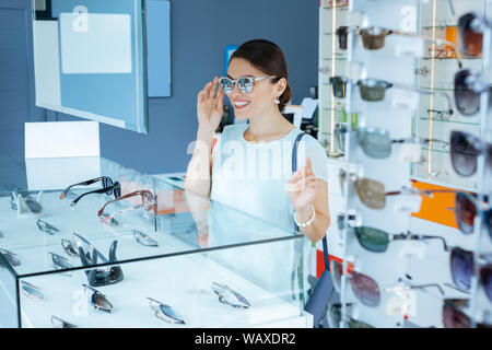 Bella bruna positivo donna tenendo la occhiali da sole Foto Stock