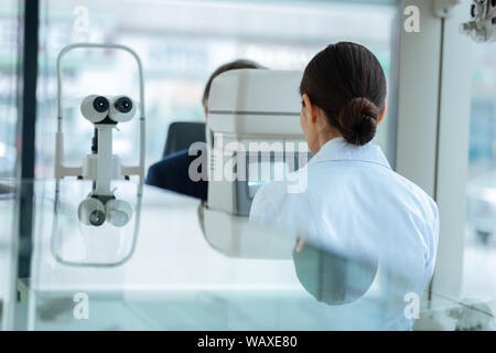 Grave bella donna controllando il suo occhio di pazienti Foto Stock