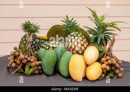 Pila di Thai fresca frutta tropicale, green mango, Giallo mango, ananas, longan, jackfruit sul tavolo luminoso con legno biege sfondo a parete Foto Stock