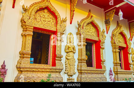 La parete laterale di Wat Phan con devata sculture e ornati in telai di finestre e decorate con imponenti rilievi dorati, modanature in forma di Naga serpenti Foto Stock