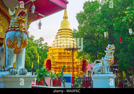 La coppia di stucco scolpito chinthe Lions nella parte anteriore del Wat Phan su Viharn hall; la tall golden chedi del tempio è visibile sullo sfondo, Chiang Mai, Foto Stock