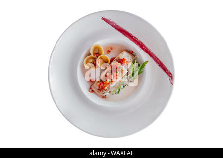 Grigliata di filetto di branzino con tortellini freschi e salsa di pomodoro in piastra bianca top view shot isolato su sfondo bianco Foto Stock