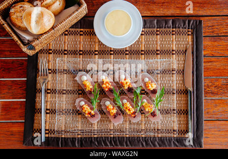 Luce antipasto sano - Freschi snapper Tataki con salsa di mango e arugulas sulla lastra di vetro sul tappetino di bambù Foto Stock