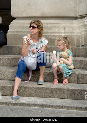 Mamma & figlia mangiare il gelato, bambina holding Teddy bear. Foto Stock