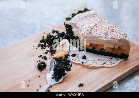 Cremoso Cheesecake banoffee con cioccolato cookie sul piatto di legno con cucchiaio. close up vista laterale shot Foto Stock