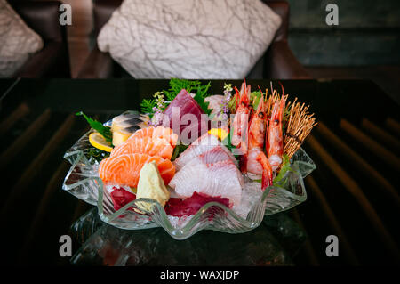 Sashimi Premium su ghiaccio, Tai pesce sashimi, Ebi sashimi, Maguro sashimi, sashimi di salmone - sfondo scuro tono caldo immagine Foto Stock