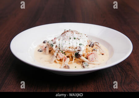 Cibo colpo di pasta italiana spaghetti con cremosa salsa Alfredo, funghi e Uovo affogato Foto Stock