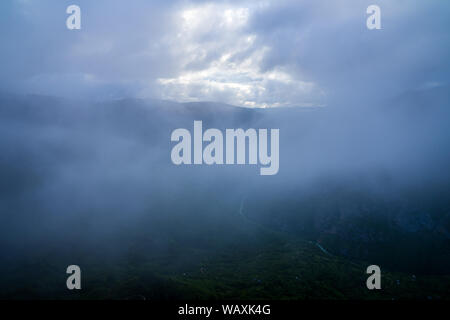 Montenegro, Dark nuvole di pioggia e nebbia nasconde infinite bellissima natura verde paesaggio del fiume Tara canyon da sopra una montagna di sera Foto Stock