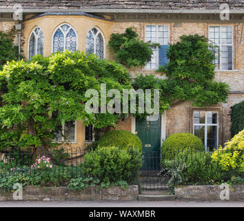 Il fogliame di glicine che copre una casa lungo Cecily hill, Cirencester, Cotswolds, Gloucestershire, Inghilterra Foto Stock