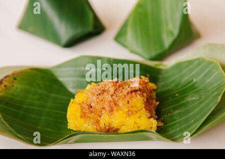 Dolce di gamberetti e noce di cocco trinciatrice su giallo di riso appiccicoso, tradizionale Thai dessert locali avvolti in foglie di banana Foto Stock