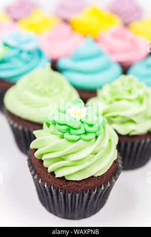 Tazza di cioccolato torte con ghiaccio o la glassa, rosa, viola, blu, giallo e verde fotografato su sfondo bianco Foto Stock