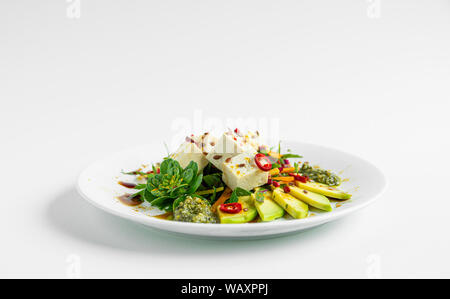 Il tofu con verdure colorate con spezie sulla piastra e sfondo bianco, isolato piatto di tofu Foto Stock