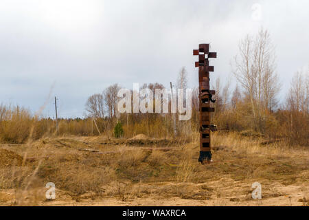 Strano tubo arrugginito bastoni fuori nel mezzo di una terra desolata, somigliante ad un totem pole Foto Stock