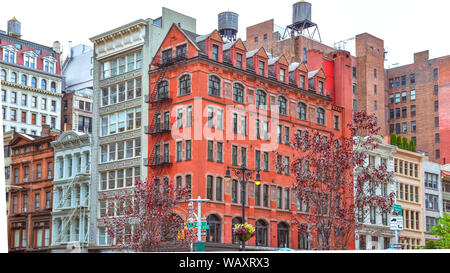 Colorati edifici in mattoni con finestre e le scale antincendio. Depositi di acqua sui tetti. New York, Stati Uniti d'America Foto Stock