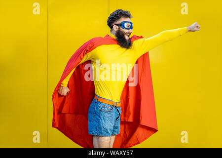 Ritratto di un uomo come un supereroe in abiti colorati e pilota gli occhiali su sfondo giallo Foto Stock