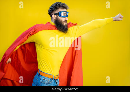 Ritratto di un uomo come un supereroe in abiti colorati e pilota gli occhiali su sfondo giallo Foto Stock