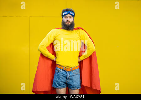 Ritratto di un uomo come un supereroe in abiti colorati e pilota gli occhiali su sfondo giallo Foto Stock