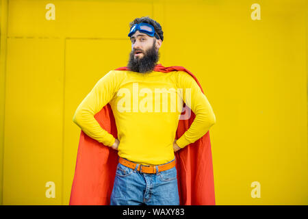 Ritratto di un uomo come un supereroe in abiti colorati e pilota gli occhiali su sfondo giallo Foto Stock